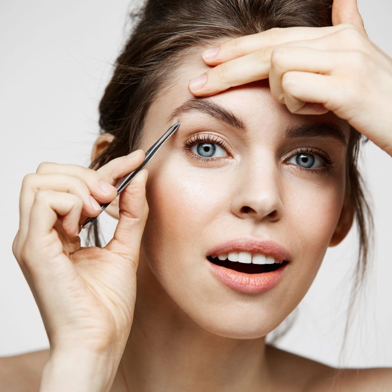 Close-up of brow shaping treatment using precision tools